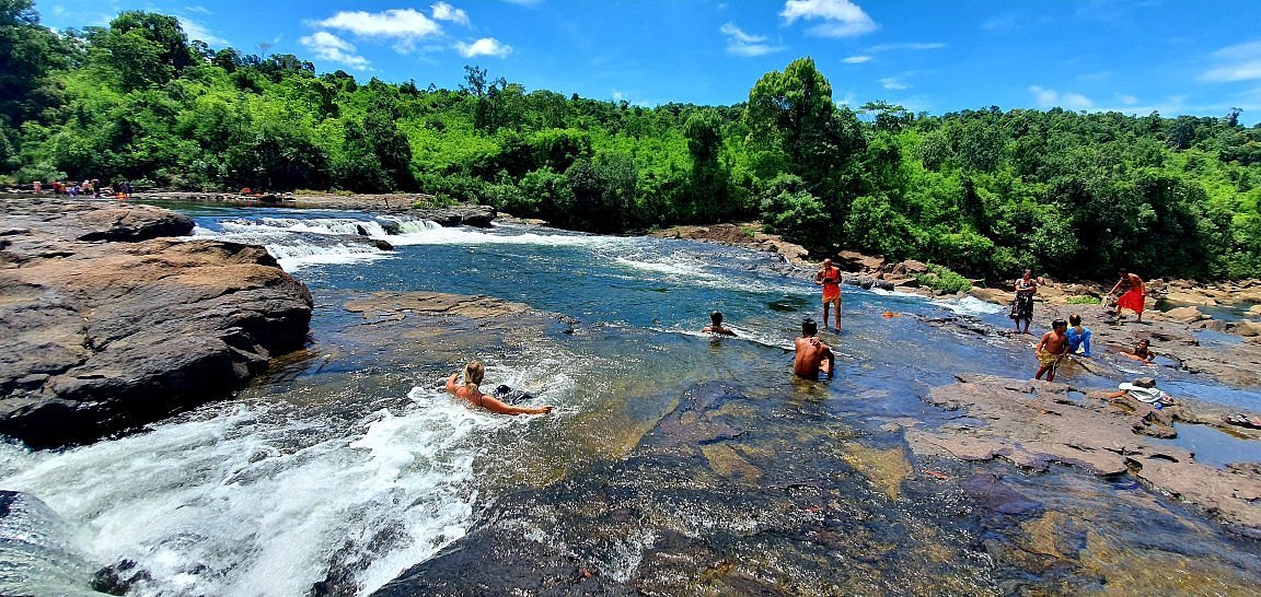 Visitors swimming and wading across the rock terraces at Tatai Waterfall, Koh Kong, Cambodia